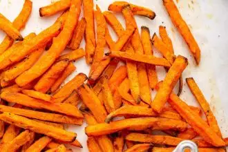 Sweet potato fries spread out near a small container of ketchup.