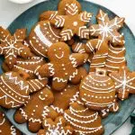 Multiple gingerbread cookies decorated with icing on a plate.