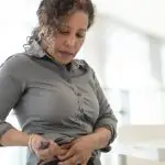 Image of a women injecting a medication pen into her stomach