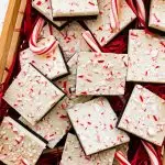 Square peppermint bark pieces stacked on top of each other in a gift box.