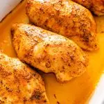 Four baked chicken breasts in a large baking dish.