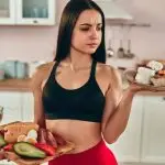 A girl with pastries and cakes on one plate and fresh fruits and vegetables on the other.