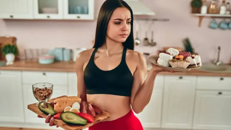 A girl with pastries and cakes on one plate and fresh fruits and vegetables on the other.