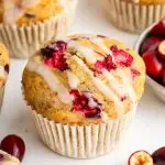 A cranberry orange muffin topped with a drizzle of an almond milk based glaze.