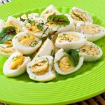 Boiled quail eggs halves on a green plate