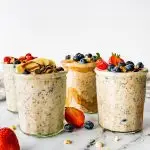 Four glass jars of overnight oats topped with fresh berries.