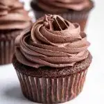 Three chocolate cupcakes topped with chocolate buttercream frosting.