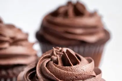 Three chocolate cupcakes topped with chocolate buttercream frosting.