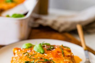 A serving of vegetarian tofu lasagna made with zucchini noodles on a white plate with a fork.