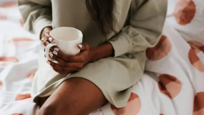 A woman drinking in bed