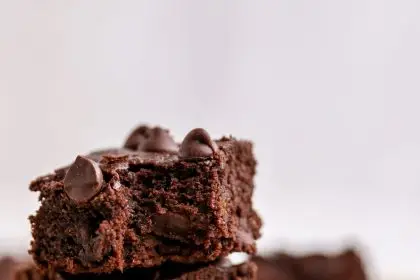 Three protein brownies stacked on top of one another. The top brownie has a bite taken out of it.