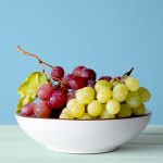 Grapes in a white bowl on wooden table